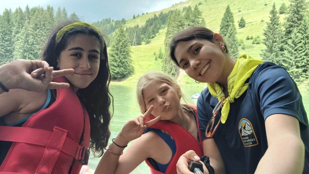 Campeurs en gilets de sauvetage rouges avec leur monitrice avant une activité sur un lac alpin