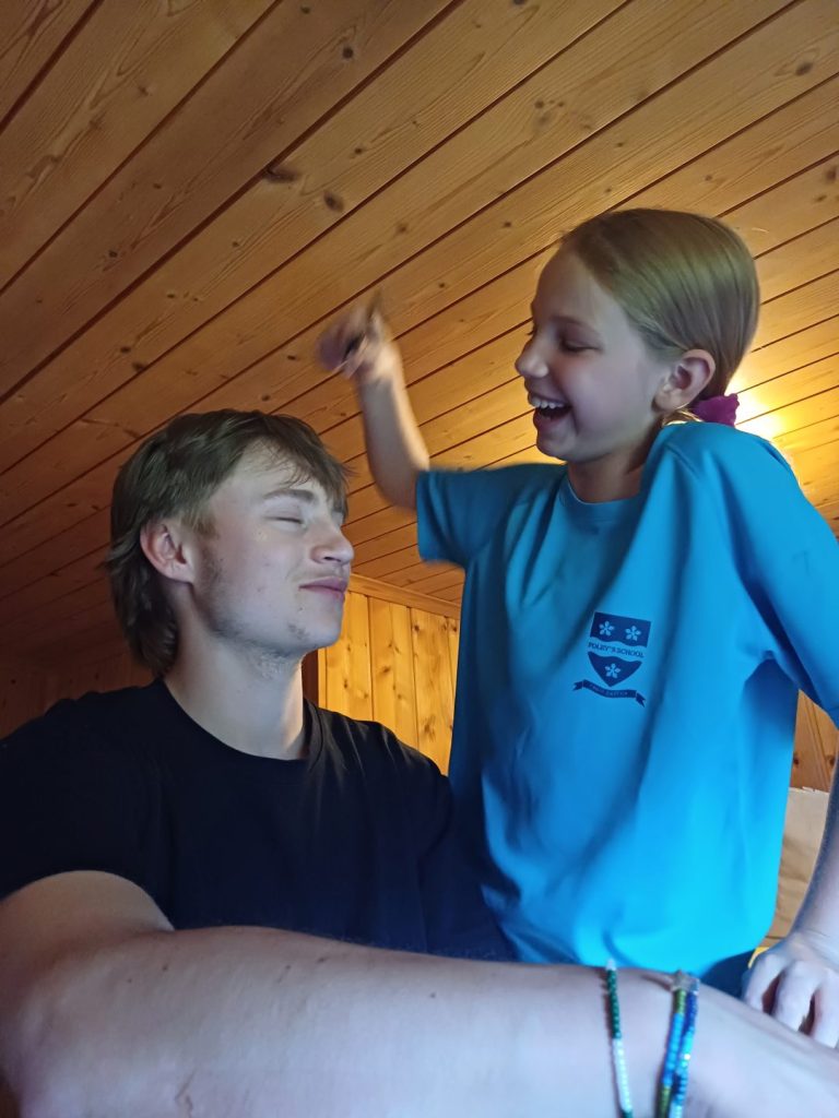 Campeur maquillant le visage d'une monitrice pendant les jeux du soir au chalet