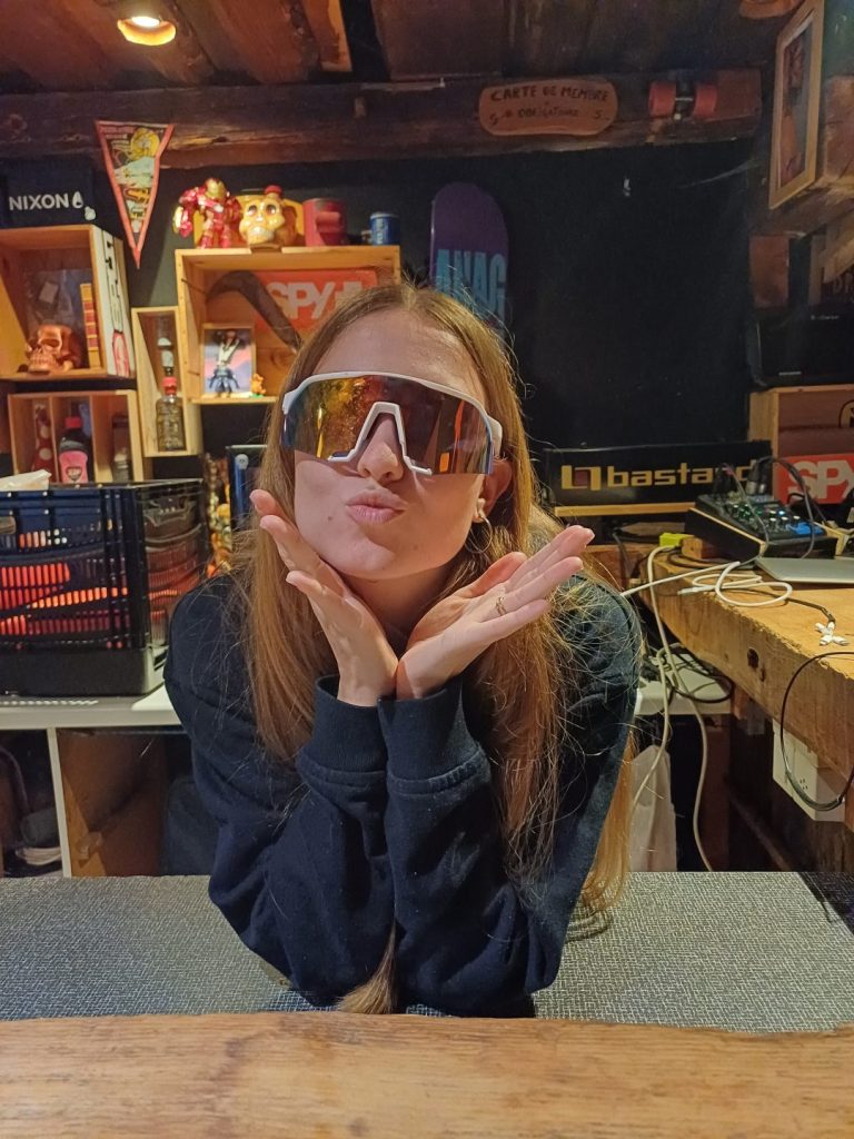 Monitrice en lunettes de soleil formant un cœur avec ses mains dans la salle commune du chalet