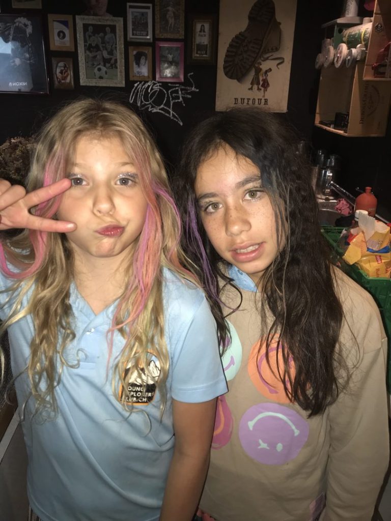 Deux jeunes campeurs en t-shirts Young Explorers Club posant dans le chalet