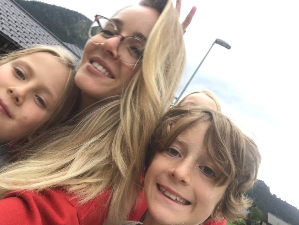 Monitrice et deux jeunes campeurs souriants pendant une excursion