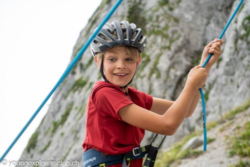 Boy in a climbing helmet holding the rope on a via ferrata