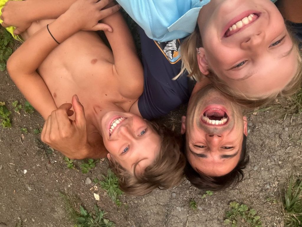 Campeurs allongés tête contre tête en cercle pour un selfie de groupe rigolo