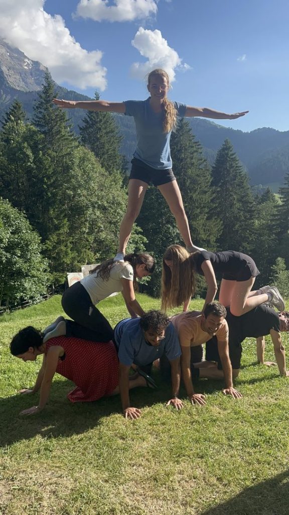 Campeurs formant une pyramide humaine, une fille en équilibre au sommet, dans un alpage