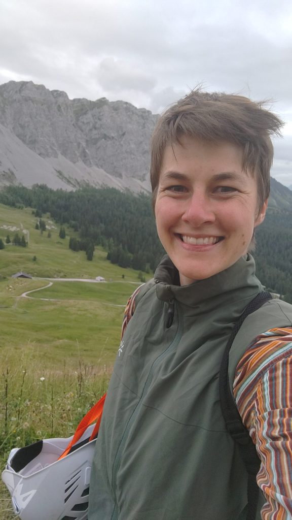 Moniteur souriant devant des alpages et des falaises calcaires
