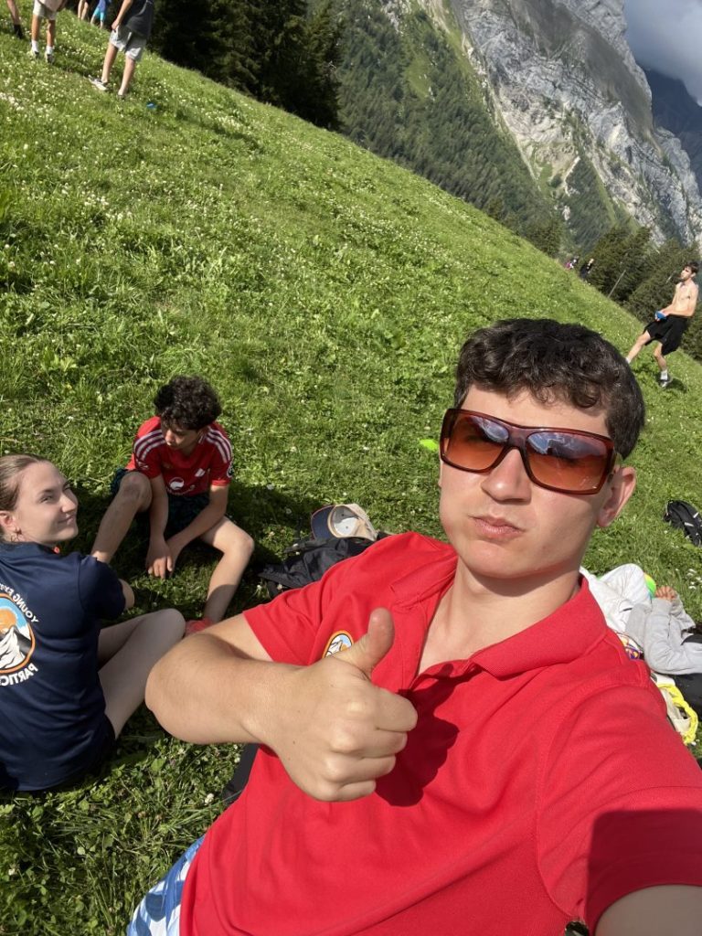 Moniteur en t-shirt rouge levant le pouce avec des campeurs sur une pente de montagne
