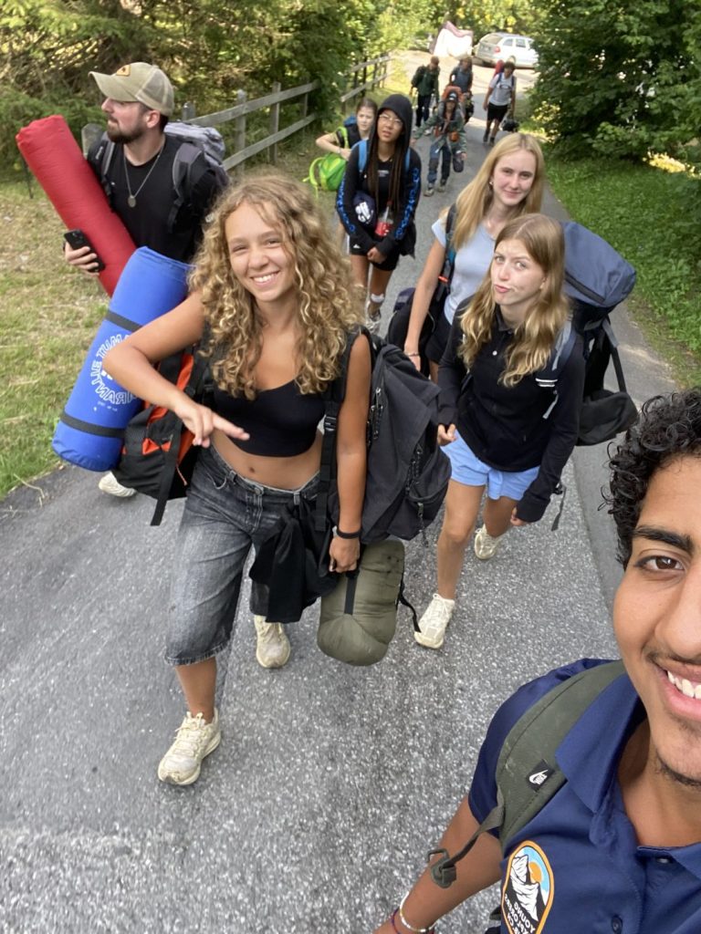 Ados chargés de sacs à dos et de matelas au départ d'un trek avec bivouac