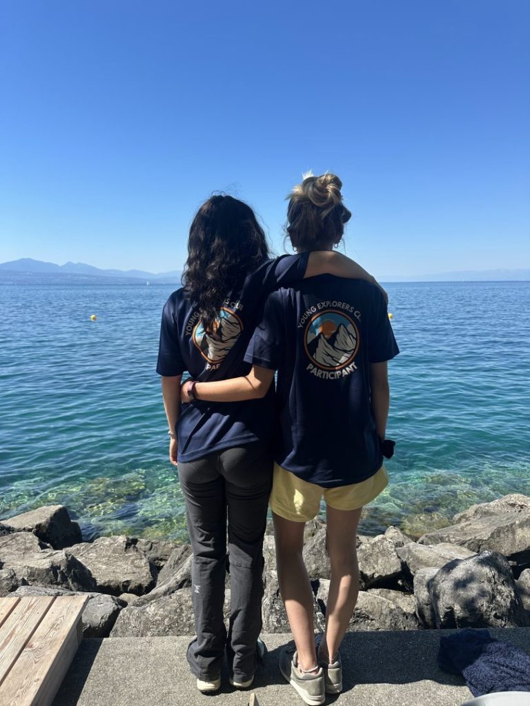 Deux moniteurs en t-shirts Young Explorers Club contemplant le lac par une journée ensoleillée
