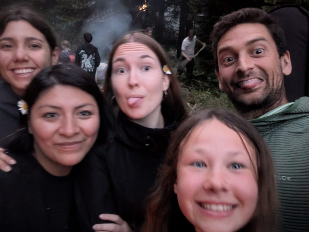 Moniteurs et campeurs faisant des grimaces sur un selfie de groupe au feu de camp, au crépuscule