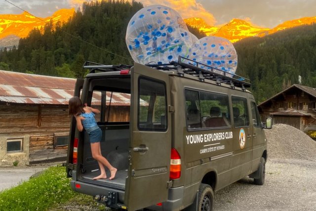 Young Explorers Club Van mit aufblasbaren Bubble Balls auf dem Dach bei Sonnenuntergang in den Bergen