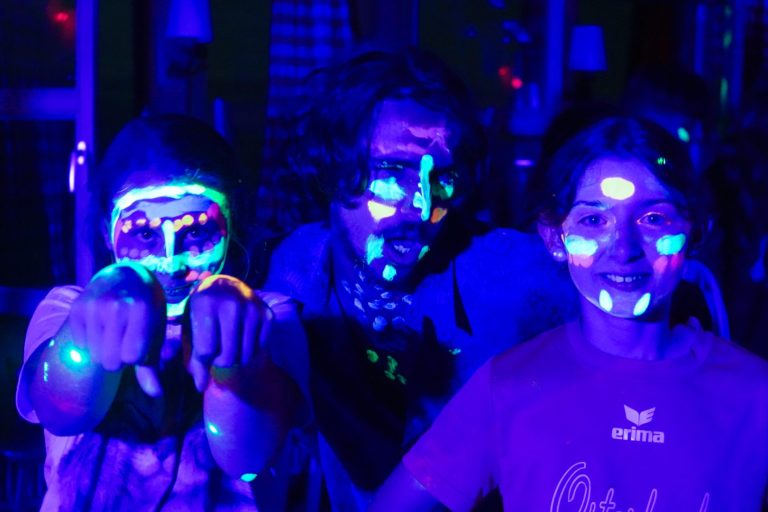 Campers with glowing UV face paint at an evening party at summer camp