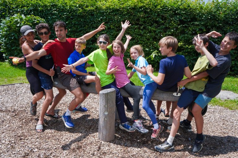 Campers and counsellors striking silly poses on a wooden bench