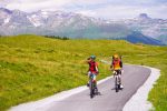 Two young cyclists riding a mountain road across high pastures on the Bike Travel Camp