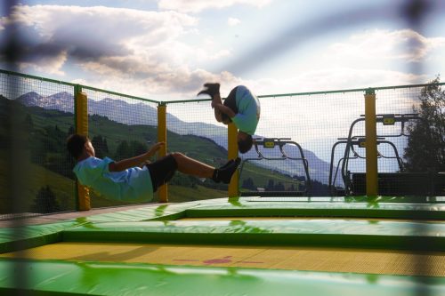 Camper doing a somersault on a trampoline with mountain views