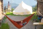 Campeur se détendant dans un hamac près d'une tente tipi, les montagnes en arrière-plan