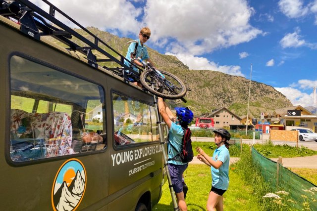 Campers loading their bikes onto the roof rack of the Young Explorers Club van