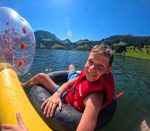 Boy in a life jacket floating on a lake with inflatable water toys at the Multisport camp