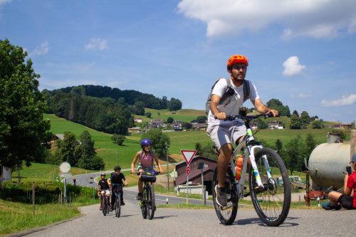 Group of young cyclists riding along a country road on a sunny summer day