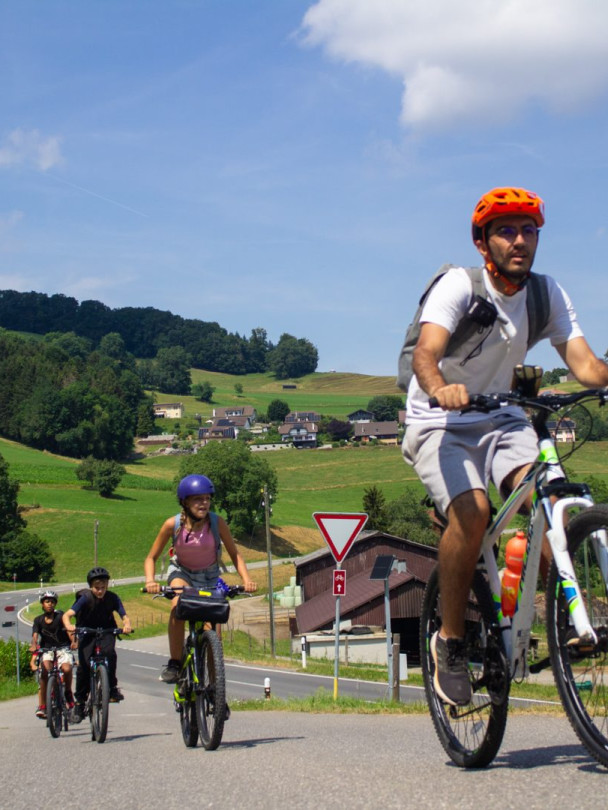 Group of young cyclists riding along a country road on a sunny summer day