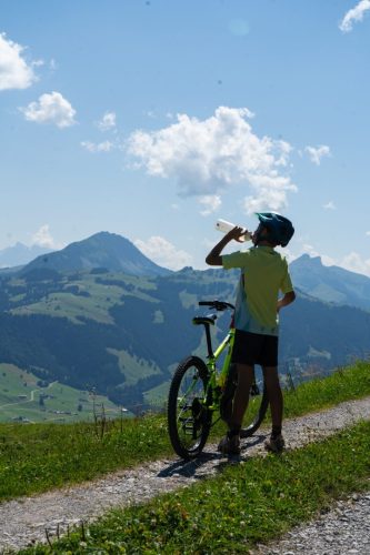 Young cyclist taking a water break beside his bike high above the valley