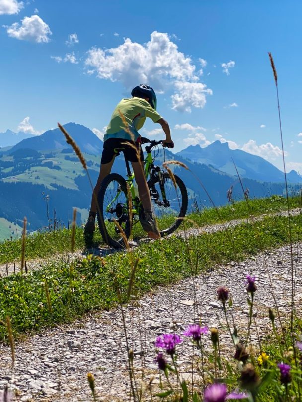Teenager mountain biking on an alpine trail above Les Diablerets at summer camp
