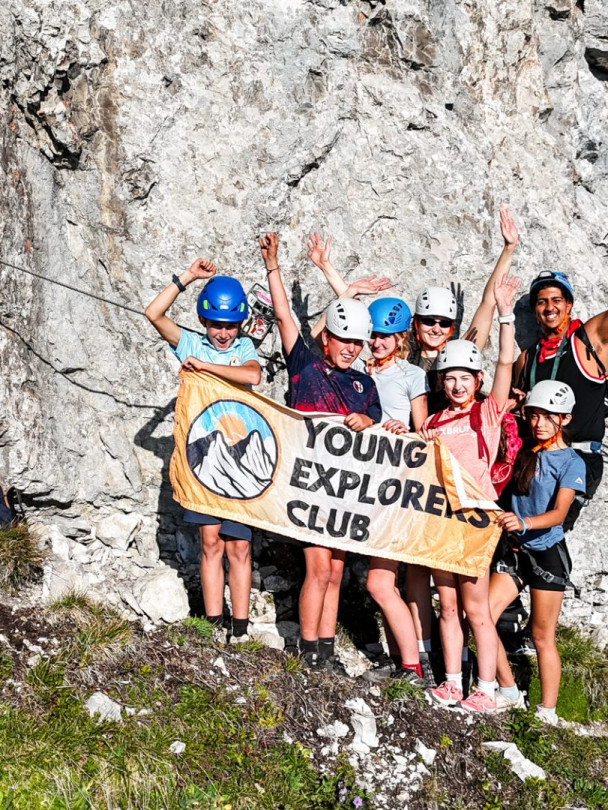 Aerial view of the climbing group holding the Young Explorers Club banner on the rock face
