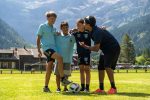 Football coach talking tactics with three young players on the pitch in the Alps