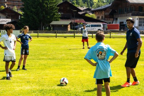 Coach leading a football drill on the pitch in Les Diablerets