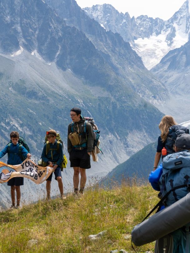 Teenagers with trekking backpacks on the Tour du Mont Blanc trail below the glaciers