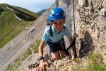 Young climber in a blue helmet on a via ferrata in Les Diablerets