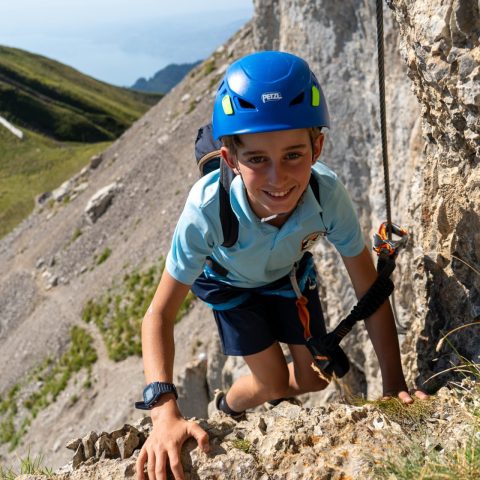 Young climber in a blue helmet on a via ferrata in Les Diablerets