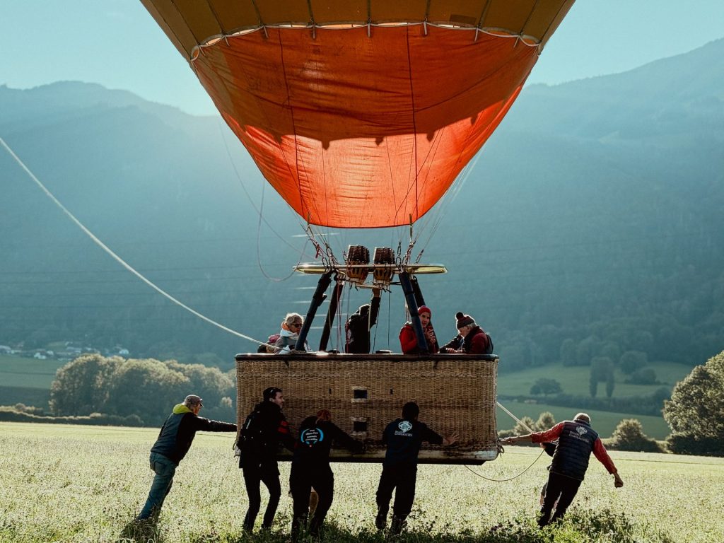 Campers and staff holding a hot air balloon basket before take-off in the Swiss Alps