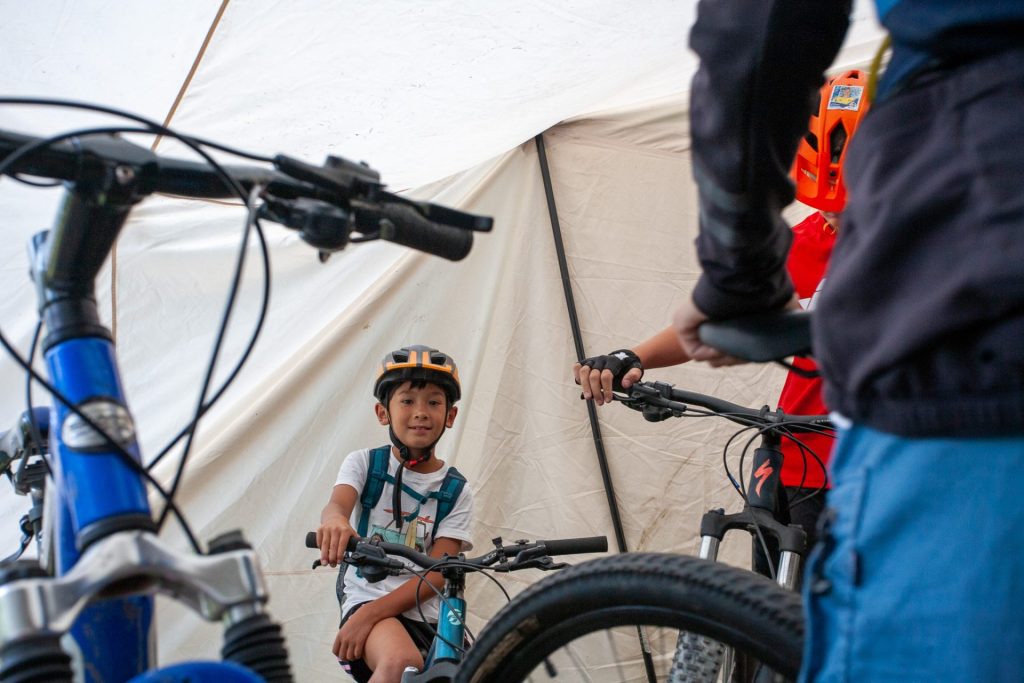 Young rider with his mountain bike beside the camp bell tent