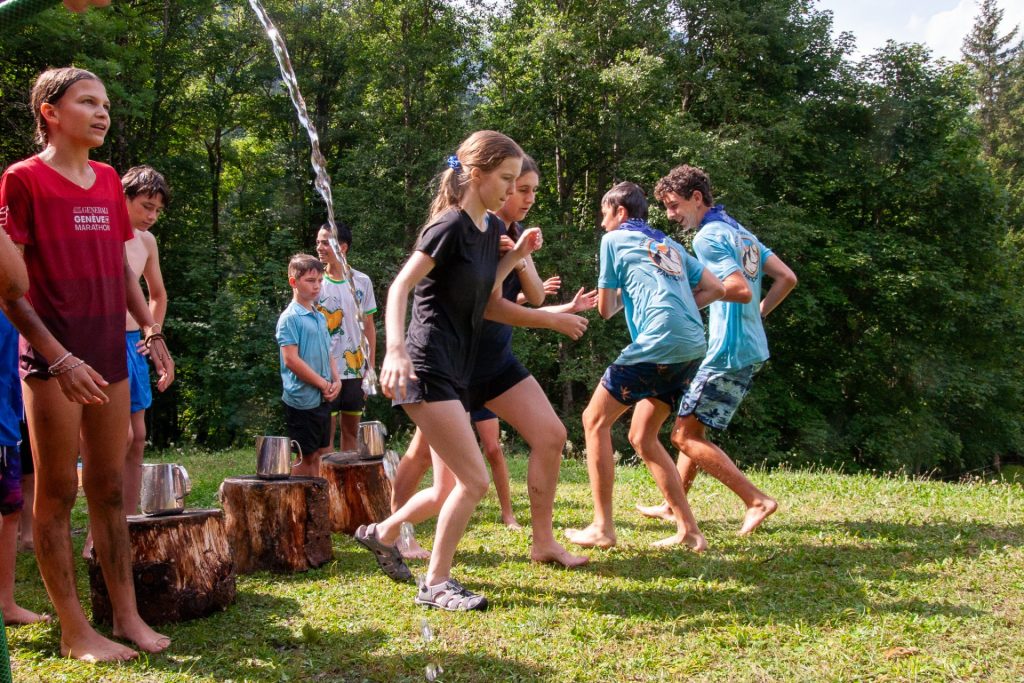 Campeurs jouant à un relais aquatique sur la pelouse au camp d'été