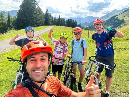 Selfie du moniteur avec des ados cyclistes levant le pouce sur une route de montagne