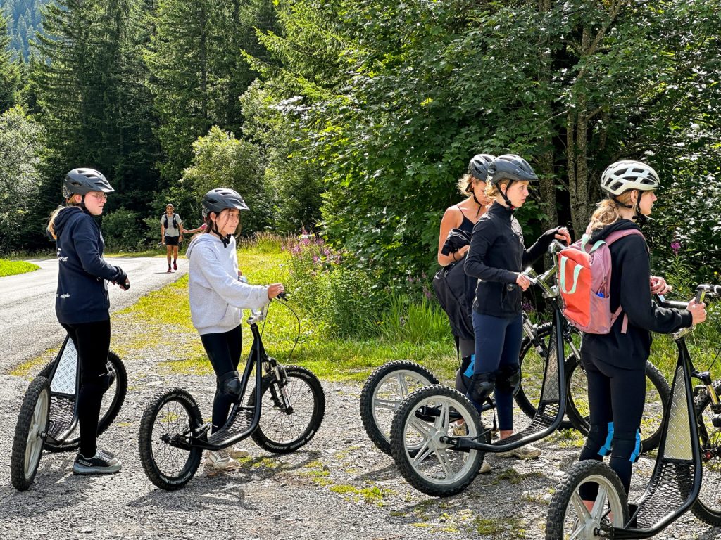 Campers in helmets lined up on downhill scooters ready to ride