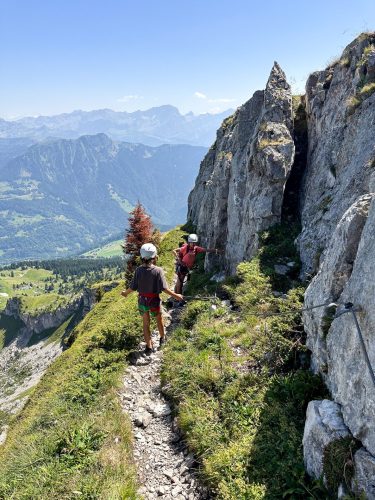 Hikers on a narrow path between limestone pinnacles high above the valley