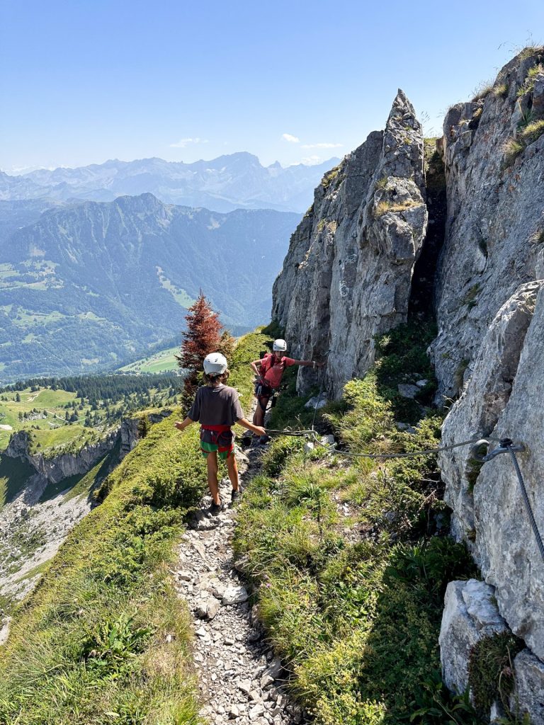 Hikers on a narrow path between limestone pinnacles high above the valley