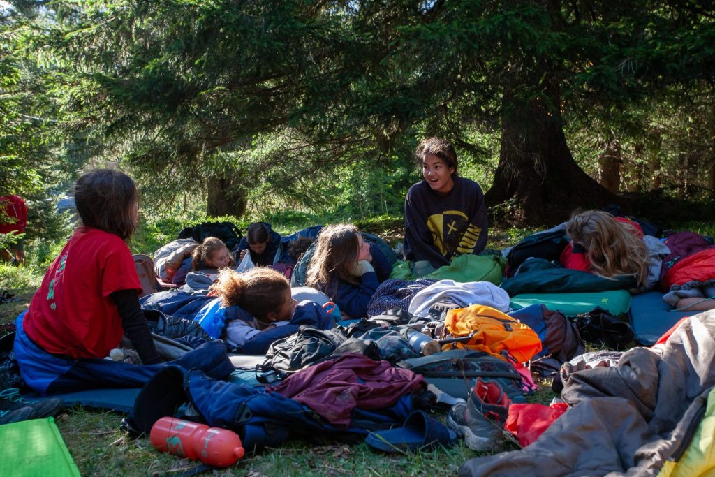 Camper wachen in ihren Schlafsäcken nach einer Nacht unter den Bäumen auf