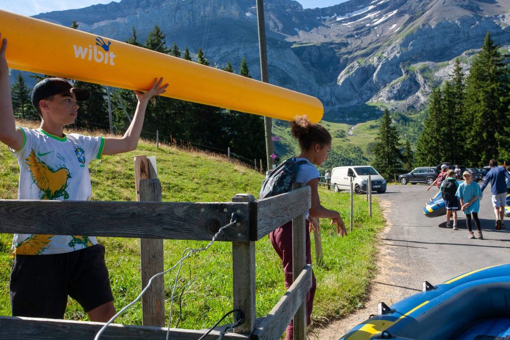 Campistas llevando un hinchable acuático hacia el lago en la montaña