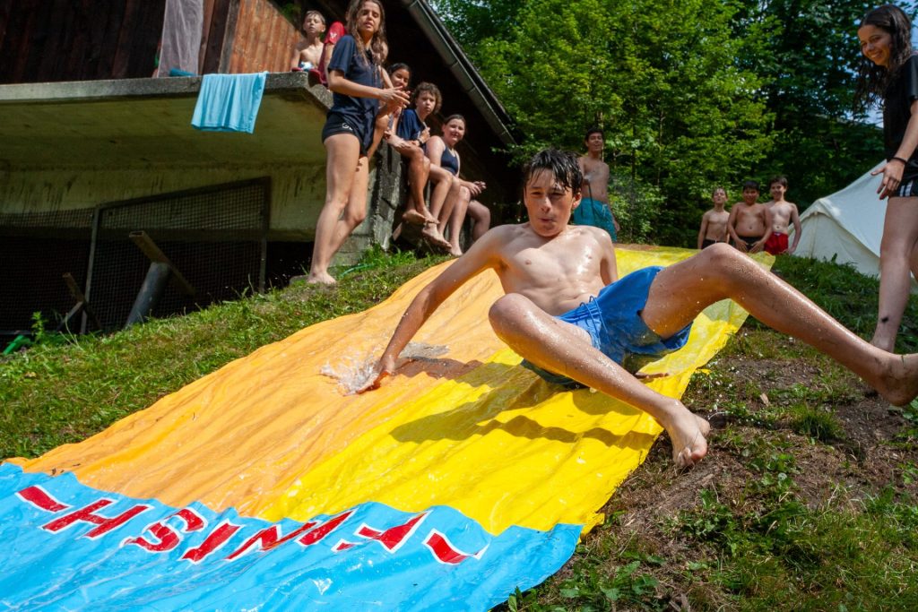 Campeur glissant sur un toboggan aquatique géant posé sur l'herbe au camp d'été