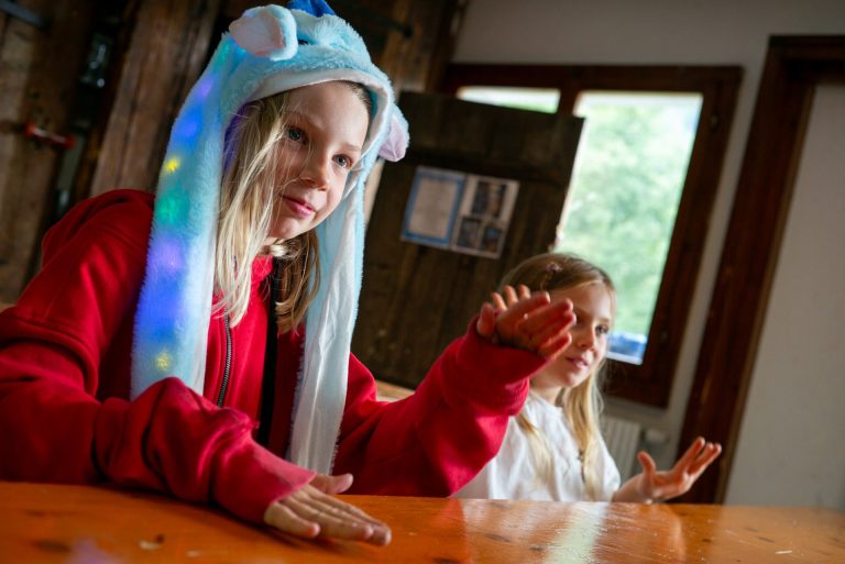 Filles dans la salle à manger du chalet pendant une veillée, l'une avec un chapeau lumineux