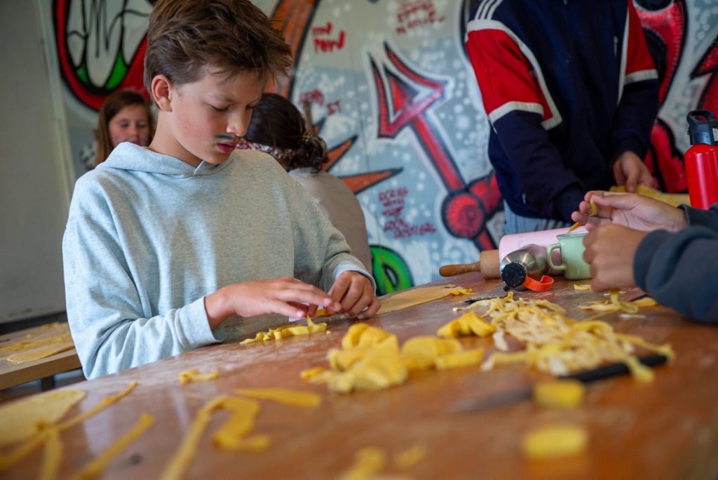 Campeur préparant des pâtes fraîches à la main pendant un atelier cuisine au camp