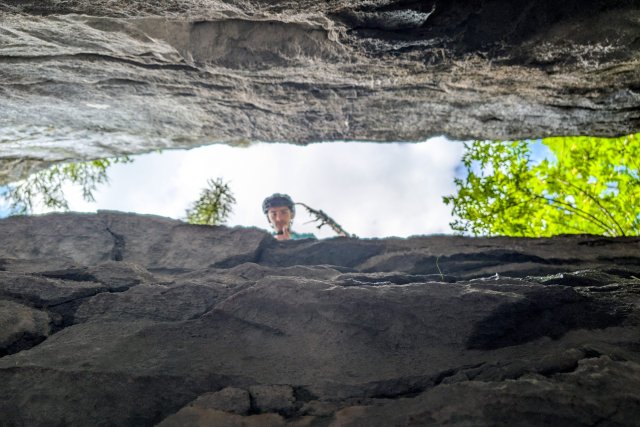 Campeur regardant dans l'ouverture d'une grotte, vu depuis l'intérieur