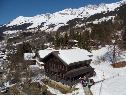 Das Chalet des Jugendcamps in Les Diablerets unterhalb eines verschneiten Berghangs