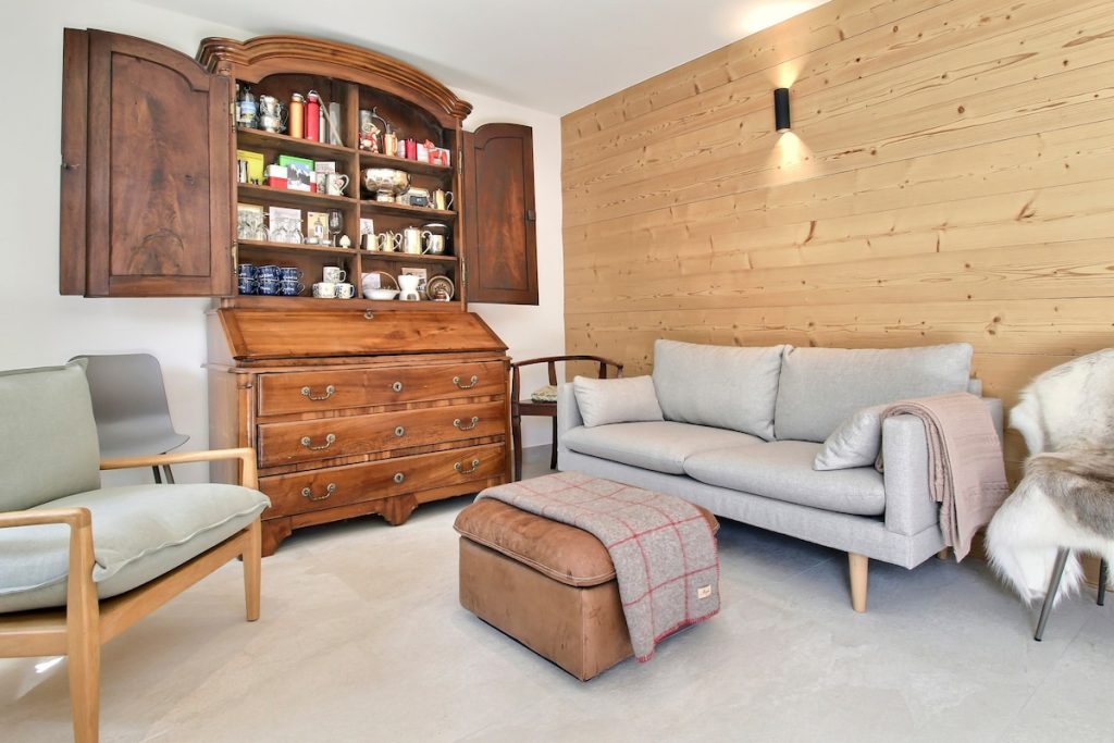 Petit salon avec une armoire ancienne en bois et un canapé au chalet de Champéry