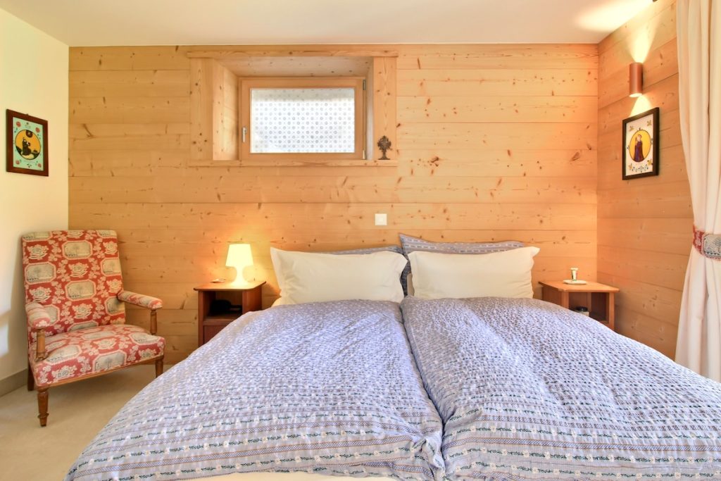 Chambre avec grand lit et fauteuil rouge au chalet de Champéry