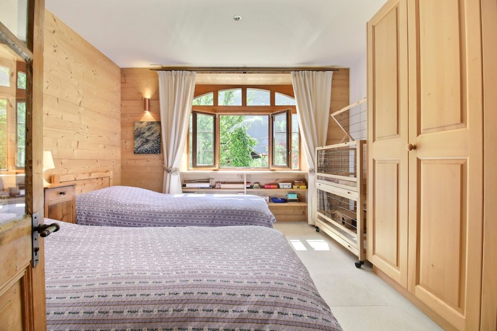 Chambre à deux lits lambrissée avec fenêtre sur les montagnes au chalet familial de Champéry