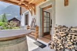 Entrance of the Champéry chalet with a stack of firewood and a wooden sled