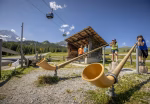 Giant alphorns beside a mountain hut with a cable car overhead